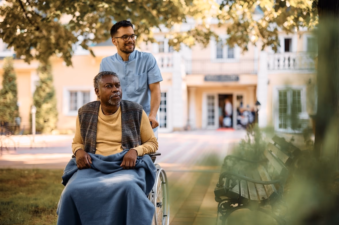 carer wheeling man in wheelchair