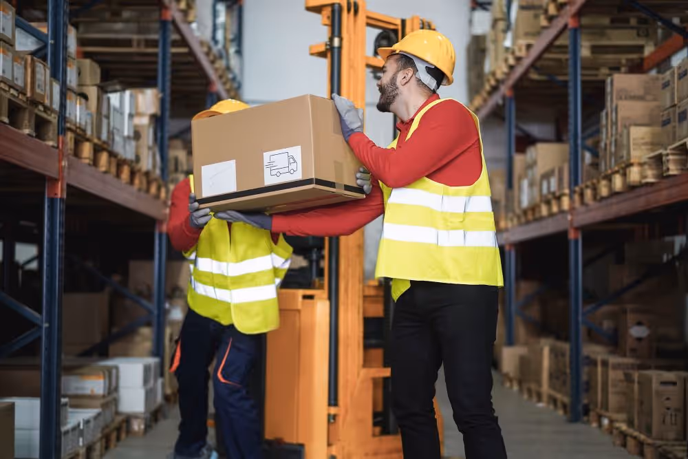 Two warehouse workers carrying a box