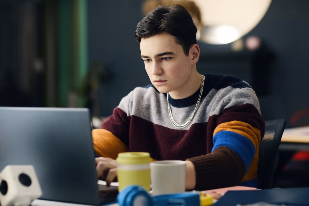 teenage boy using laptop in his room