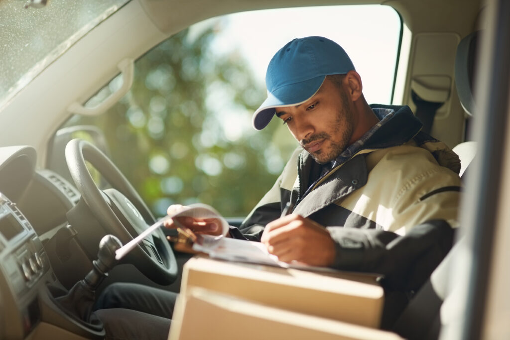 Delivery driver reading addresses while sitting in a delivery van