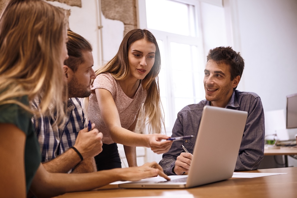 smiling colleagues pointing at laptop